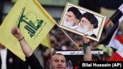 A Hezbollah supporter chants slogans, as he holds a picture of the late Iran revolutionary founder Ayatollah Khomeini, left, and Iran's Supreme Leader Ayatollah Ali Khamenei, right, during a Hezbollah-organized rally titled "in solidarity with oppressed Y