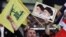 A Hezbollah supporter chants slogans, as he holds a picture of the late Iran revolutionary founder Ayatollah Khomeini, left, and Iran's Supreme Leader Ayatollah Ali Khamenei, right. File photo