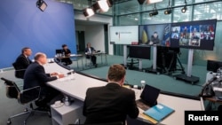 Ukrainian President Volodymyr Zelenskiy appears on a screen as German Chancellor Olaf Scholz (second left) oversees a virtual G7 leaders meeting at the Chancellery in Berlin on October 11.
