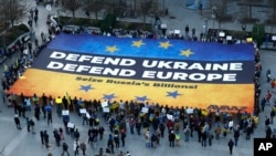 Banner chemând la apărarea Ucrainei și Europei, desfășurat de activiști europeni în fața clădirii Consiliului European de la Bruxelles, înainte de un summit european în luna martie curent 