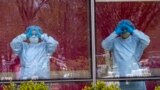 Nurses gesture from inside the hospital as others hold a demonstration outside Jacobi Medical Center to protest a new policy by the hospital requiring a doctor's note for paid sick leave, Friday, April 17, 2020, in the Bronx borough of New York.