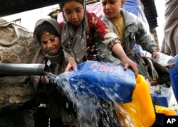 A girl collects water from a public tap as others try to cut the line. (file photo)
