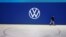 An employee of Volkswagen AG walks past the revised logo 