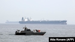 Tanker Xarq adasındakı neft terminalına yan almağa hazırlaşarkən, İran hərbi kateri ərazidə patrul çəkir.