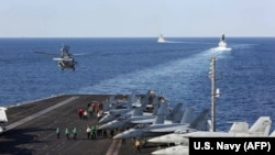 The aircraft carrier USS Abraham Lincoln transits the Strait of Hormuz as an MH-60S Sea Hawk helicopter lifts off from the flight deck, November 19, 2019