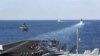 FILE - The aircraft carrier USS Abraham Lincoln transits the Strait of Hormuz as an MH-60S Sea Hawk helicopter lifts off from the flight deck, November 19, 2019