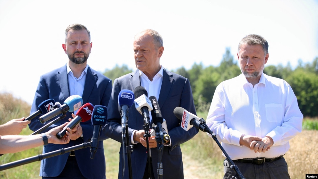 Premierul polonez Donald Tusk (centru) la conferința de presă organizată lângă locul unde a căzut racheta de croazieră.