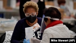 Election officials handle ballots during an audit in Marietta, Georgia, on November 16, 2020. The indictment includes charges of orchestrating an election interference campaign using political groups in Florida, Georgia, and California.