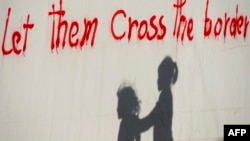 Silueta djece pored zida na kojem je ispisan grafit "Dopustite im da pređu granicu", zabilježeno nedaleko od mjesta Idomeni, Makedonija, maj 2016.