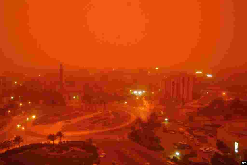 A sand storm hits the center of Baghdad, which is also shrouded in smoke from burning oil trenches.