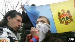 Un protestatar din Moldova scrie un slogan pe o mască ce acoperă fața, 10 aprilie 2009, Chișinău