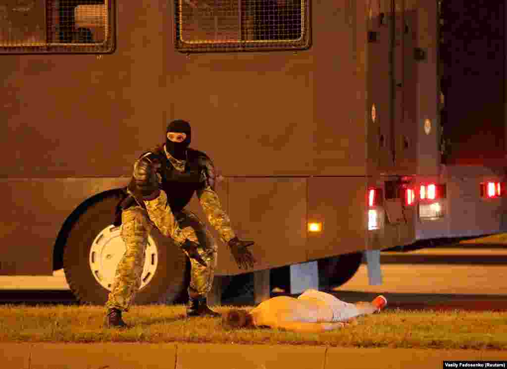 A law enforcement officer gestures next to a seriously injured man during clashes between police and opposition supporters after polls closed in Belarus&#39;s presidential election on August 9. The opposition says the vote was rigged. Officials said incumbent President Alyaksandr Lukashenka won a landslide victory. (Reuters/Vasily Fedosenko)