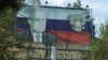 A view through a car window shows a board displaying a Russian state flag and an image of President Vladimir Putin in Stepanakert after exodus of ethnic Armenians from Nagorno-Karabakh, October 2, 2023.