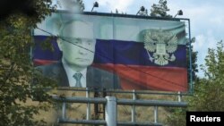 A view through a car window shows a board displaying a Russian state flag and an image of President Vladimir Putin in Stepanakert after exodus of ethnic Armenians from Nagorno-Karabakh, October 2, 2023.
