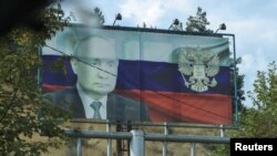 A board displaying a Russian state flag and an image of President Vladimir Putin in Stepanakert following an Azeri military operation conducted and the mass exodus of ethnic Armenians from Nagorno-Karabakh, October 2, 2023.