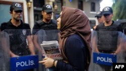 A woman holds a Ozgur Gundem newspaper in front of a police barricade in Istanbul in August.