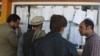 Afghan election observers check the voting results put on display at a polling center after ballots in the country's legislative election were counted in Kabul on October 22. 