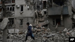 A woman walks past the debris of the destroyed house after a recent Russian air strike in Chasiv Yar on November 27. Shelling by Russian forces struck several areas in eastern and southern Ukraine as utility crews continued a scramble to restore power, water, and heating.