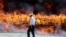 An Iranian policeman walks past a cloud of smoke rising from a pile of drugs during an incineration ceremony of some 50 tons of illicit drugs in an annual ritual in Tehran, June 26, 2014
