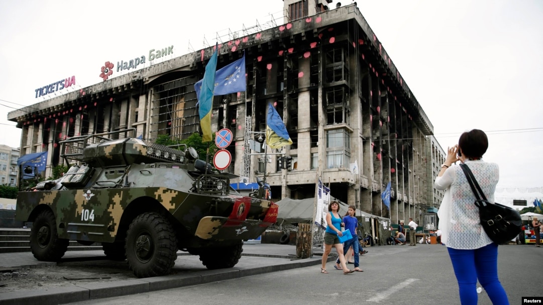 A woman takes a picture of an armoured vehicle left as a monument on Kyiv's Independence Square, known as the "Maidan."