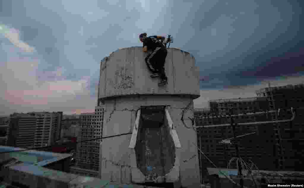 Vad Him pulls himself onto a structure on a rooftop in Moscow.