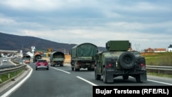 Disa automjete të FSK-së shihen duke udhëtuar përmes një rruge diku në Kosovë.