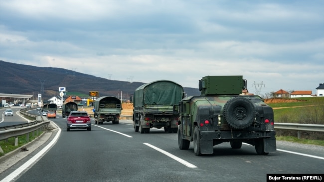 Disa automjete të FSK-së shihen duke udhëtuar përmes një rruge diku në Kosovë.