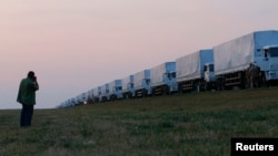 A man takes a picture of a Russian convoy of trucks carrying what Moscow says is humanitarian aid for Ukraine after the convoy stopped along a road near the Russian city of Yelets on August 12.