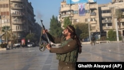 A Syrian opposition fighter shoots in the air in downtown Aleppo on November 30. 