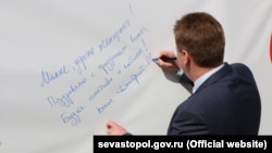 Дмитро Овсянников підписує вітальну листівку. Севастополь, 8 березня 2017 року