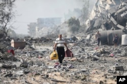 Palestinienii trec pe lângă clădirile distruse în bombardamentul israelian de la al-Zahra, la periferia orașului Gaza.