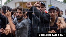 Migrants stand behind a fence inside a newly built refugee camp south of Vilnius in August 2021.