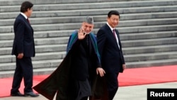 Afghan President Hamid Karzai (center) and Chinese President Xi Jinping (right) respond to children waving the national flags of their two countries at a welcoming ceremony outside the Great Hall of the People in Beijing on September 27. 