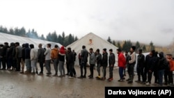 Migrants wait in line to receive food from an aid group at the Vucjak refugee camp near the Bosnia-Croatia border.