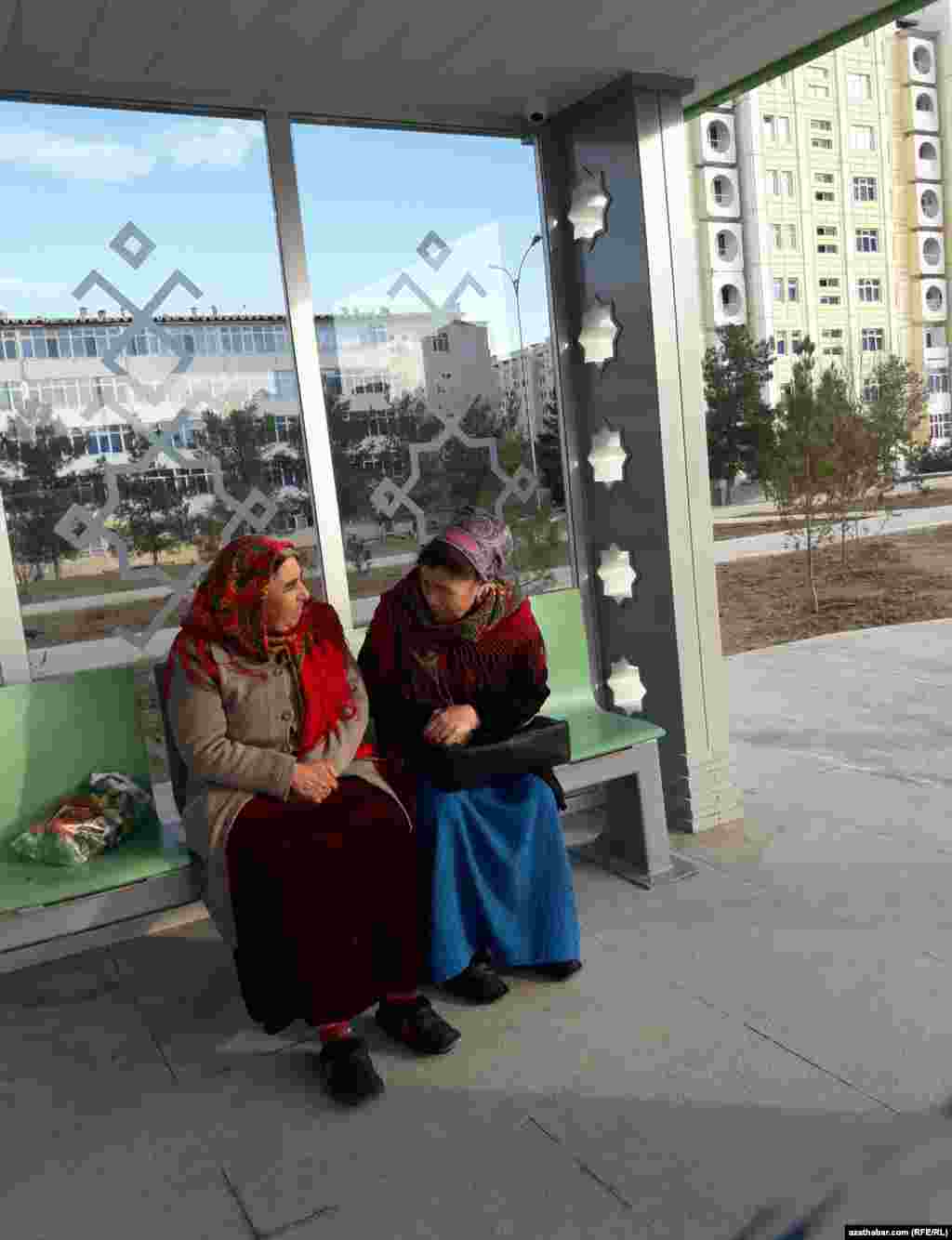 Aşgabatda duralgada awtobusa garaşyp oturan aýallar.