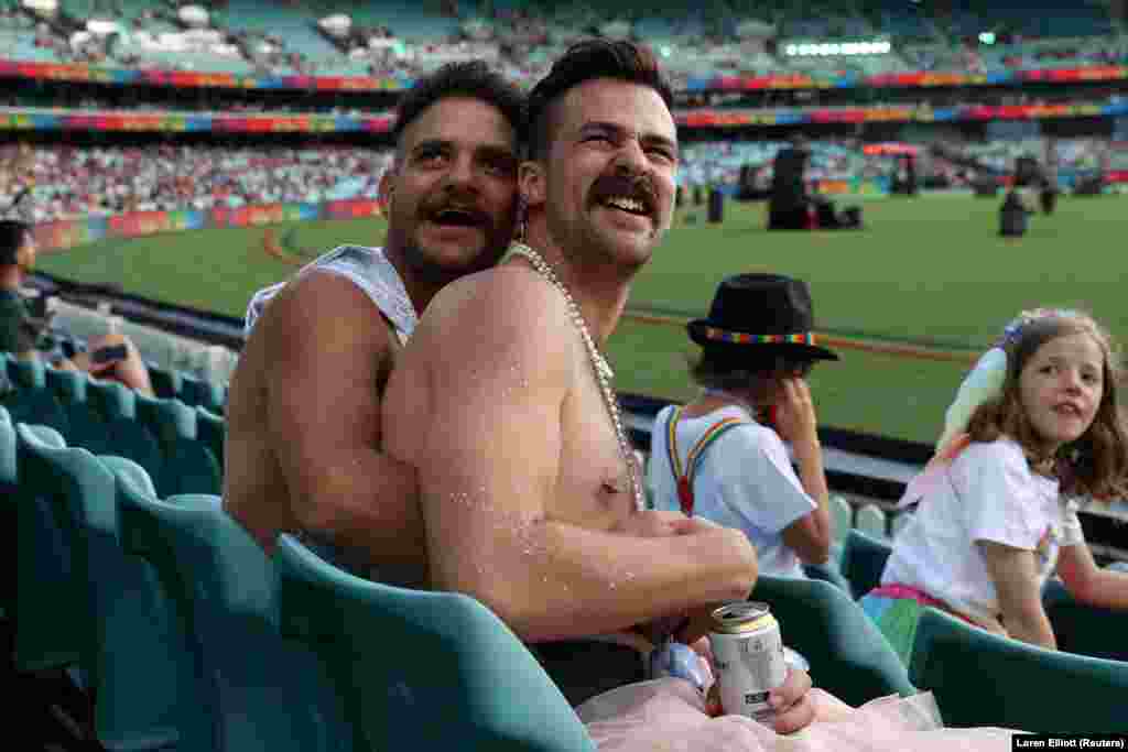 Meleg pár ünnepel Sydneyben, a távolságtartási előírásokat betartva, egy krikett stadionban.
