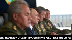 Președintele rus Vladimir Putin (centru), ministrul Apărării Serghei Șoigu (stânga) și șeful Statului Major General al forțelor armate ale Rusiei, Valeri Gherasimov (dreapta), observă exercițiile militare din septembrie 2021.