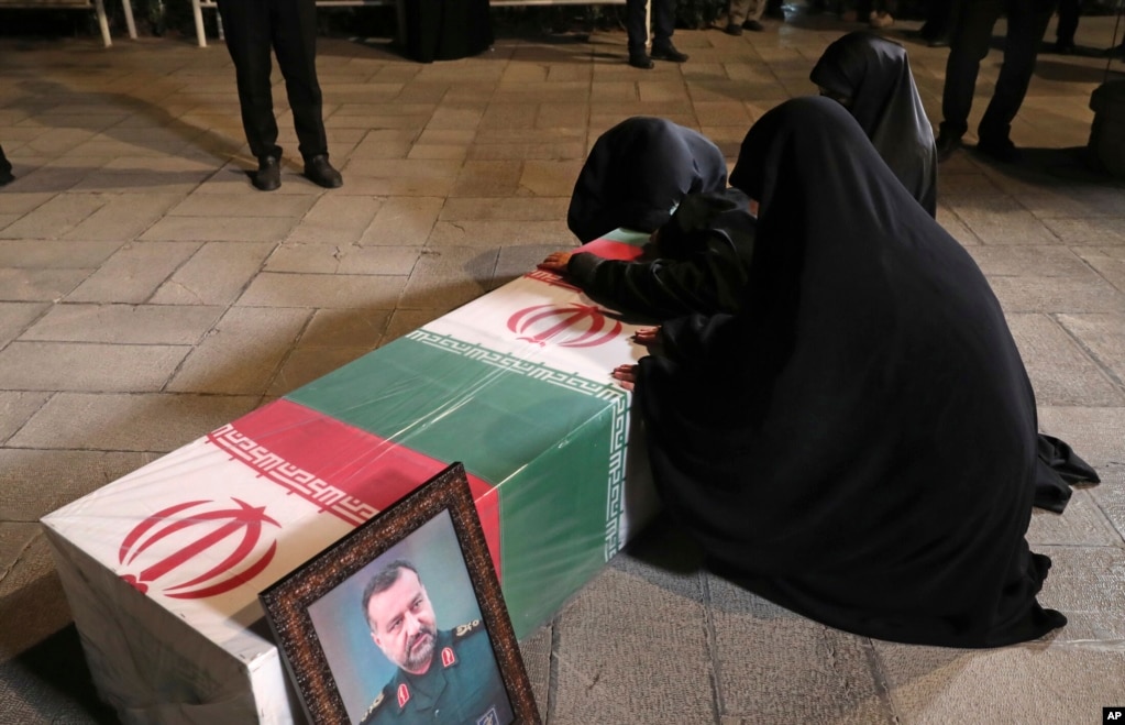 Relatives of Musavi mourn over his flag-draped coffin at the supreme leader's office compound in Tehran on December 28, 2023.