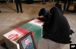 Relatives of Musavi mourn over his flag-draped coffin at the supreme leader's office compound in Tehran on December 28, 2023.