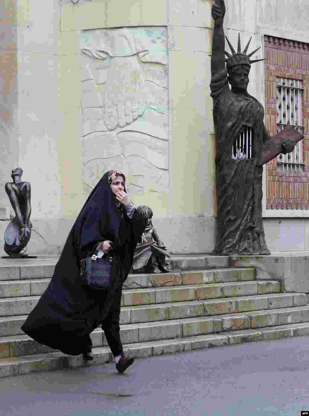 A woman walks past a mock Statue of Liberty decorated with prison bars outside the main building of the former U.S. Embassy in Tehran. 