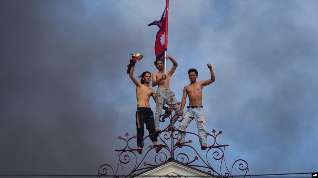 معترضان جوان نپالی بر روی ساختمان آتش‌گرفته مقر نخست‌وزیر