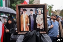 Un manifestant din Teheran ține în mână o fotografie cu liderul suprem iranian Ali Khamenei (stânga), liderul Hezbollah Hassan Nasrallah (centru) și generalul iranian Qasem Soleimani, care a fost ucis într-un atac al unei drone americane în Irak în ianuarie 2020.