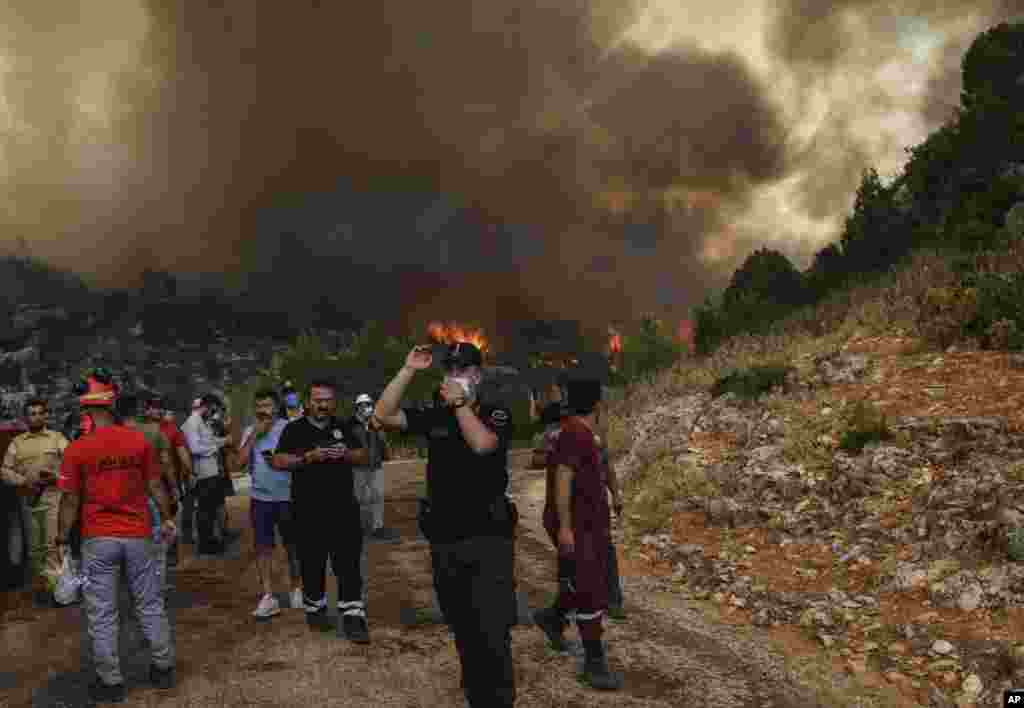 People run away in the fire-devastating Sirtkoy village, near Manavgat, Antalya, Turkey, Sunday, Aug. 1, 2021.