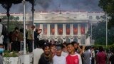 Протестиращи срещу решение на властите в Непал да ограничат достъпа до социалните мрежи си правят селфи на фона на горящия дворец Сингха Дурбар, който се използва от правителството и парламента на страната, 9 септември 2025 г.