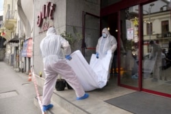 Forensic workers carry the body of Gholamreza Mansuri out of the hotel in downtown Bucharest.