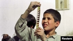 An Afghan boy examines a strip of film snatched from the flames of a bonfire lit by the Taliban to destroy cinema reels in Kabul in 1996.