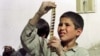 An Afghan boy examines a strip of film snatched from the flames of a bonfire lit by the Taliban to destroy cinema reels in Kabul in 1996. 