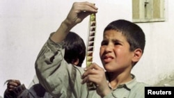 Dječak gleda na negativ koji je uspio da spasi iz vatre koju su zapalili talibani kako bi uništili filmske trake, Kabul, 1996.