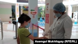 Медсестра, измеряющая температуру школьника у входа в гимназию № 67. Нур-Султан, 27 августа 2020 года.