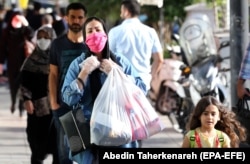 Бетіне маска таққан әйел кішкентай қызды ертіп, Тегеран көшесінде кетіп барады. Иран, 14 маусым 2020 жыл.